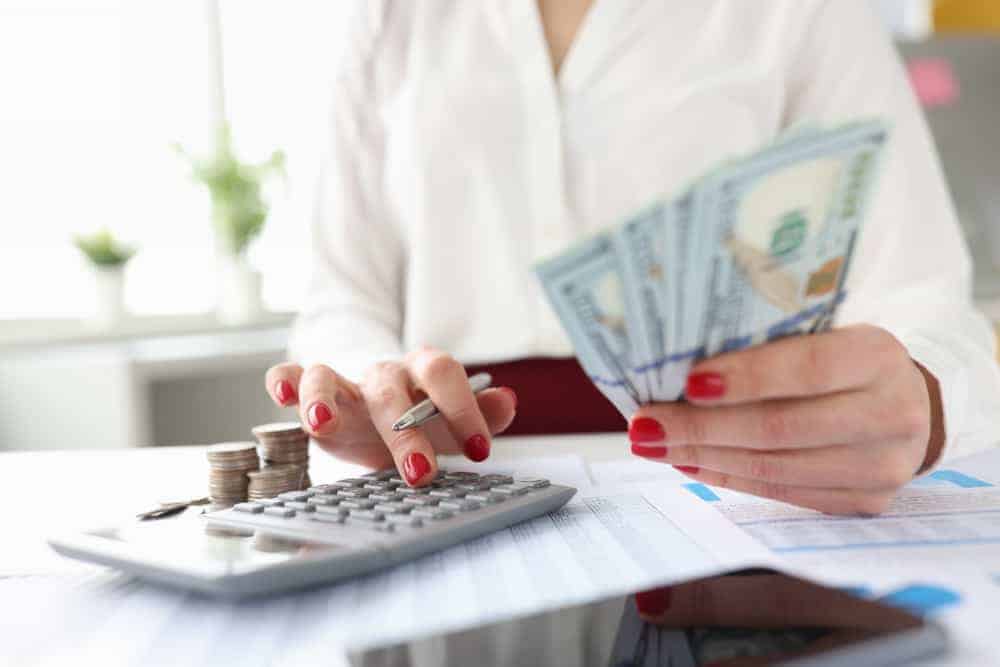 woman holds american banknotes her hands works calculator